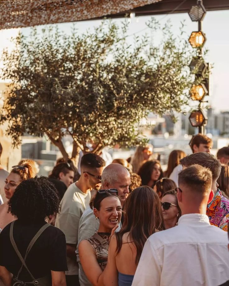 Guests socialising at a stylish rooftop event in Barcelona, surrounded by greenery and warm ambient lighting.