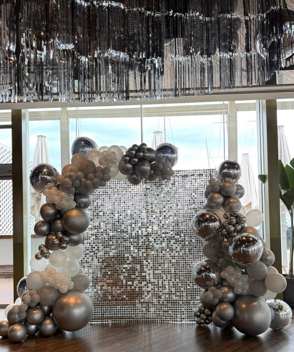 Balloon decoration installation with an elegant garland and event backdrop for a celebration.