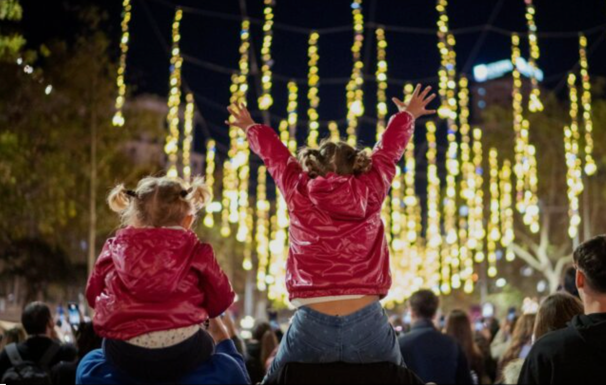 Warm Christmas evening in Barcelona: a family walking with two children under sparkling holiday lights.
