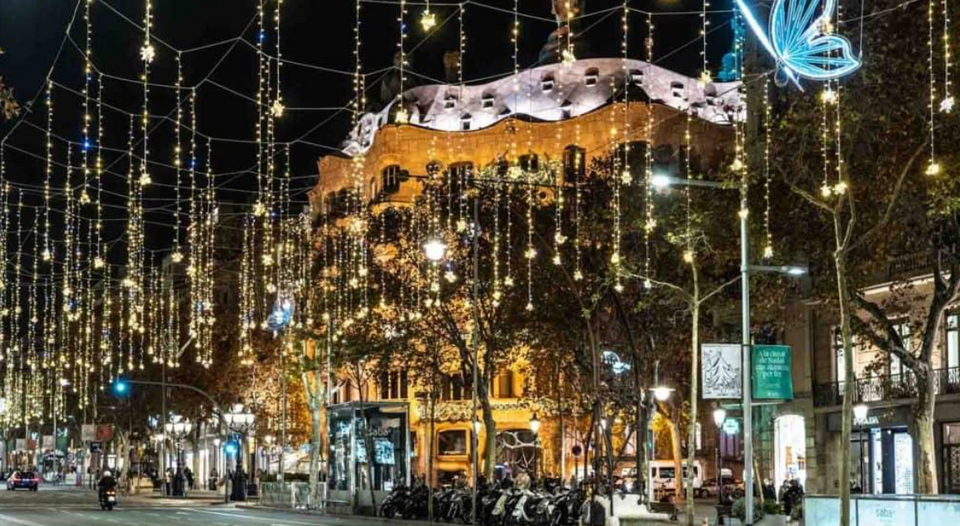Christmas lights illuminating a Barcelona street at night, with glowing arches and festive decorations creating a warm holiday atmosphere.