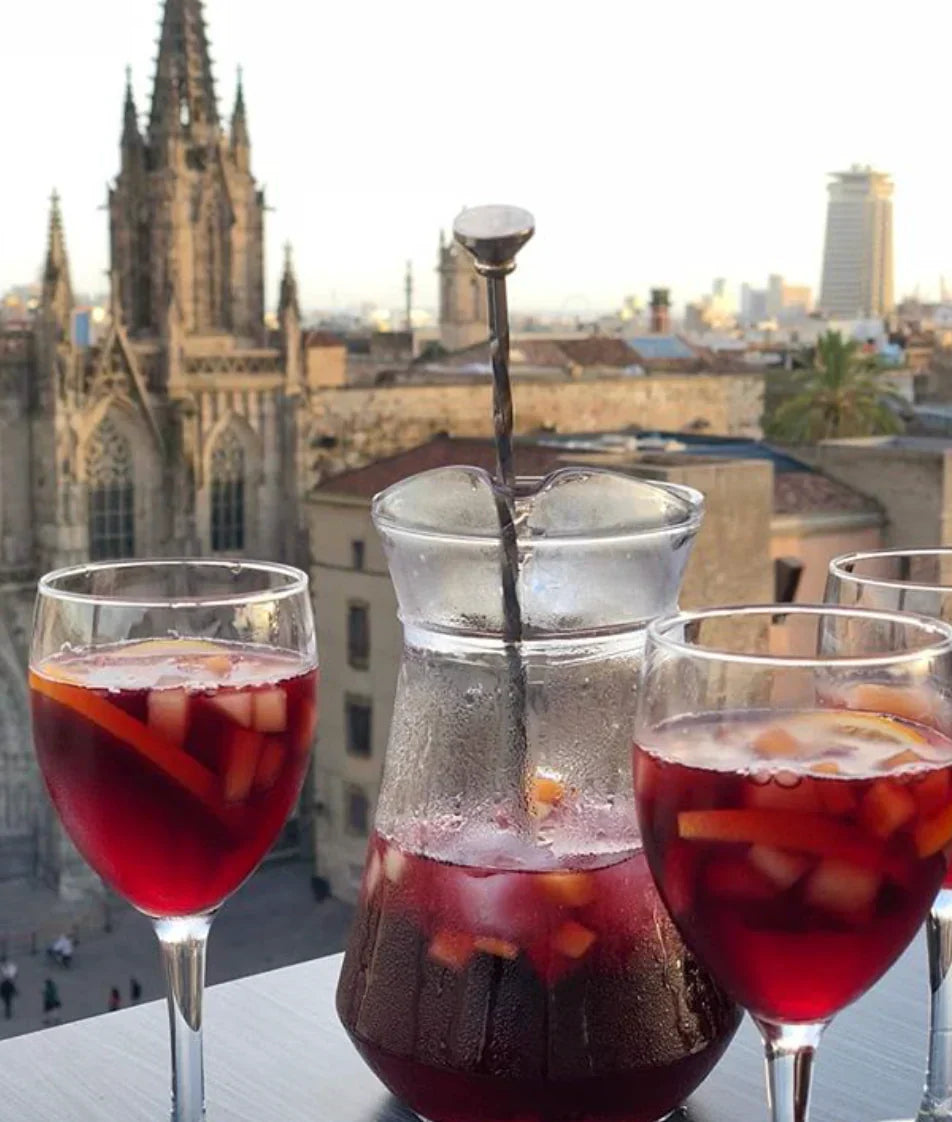Pitcher and glasses of sangria on a rooftop terrace in Barcelona with city skyline view, perfect hen party drinks and summer celebration vibes by Straws ’n Berries.