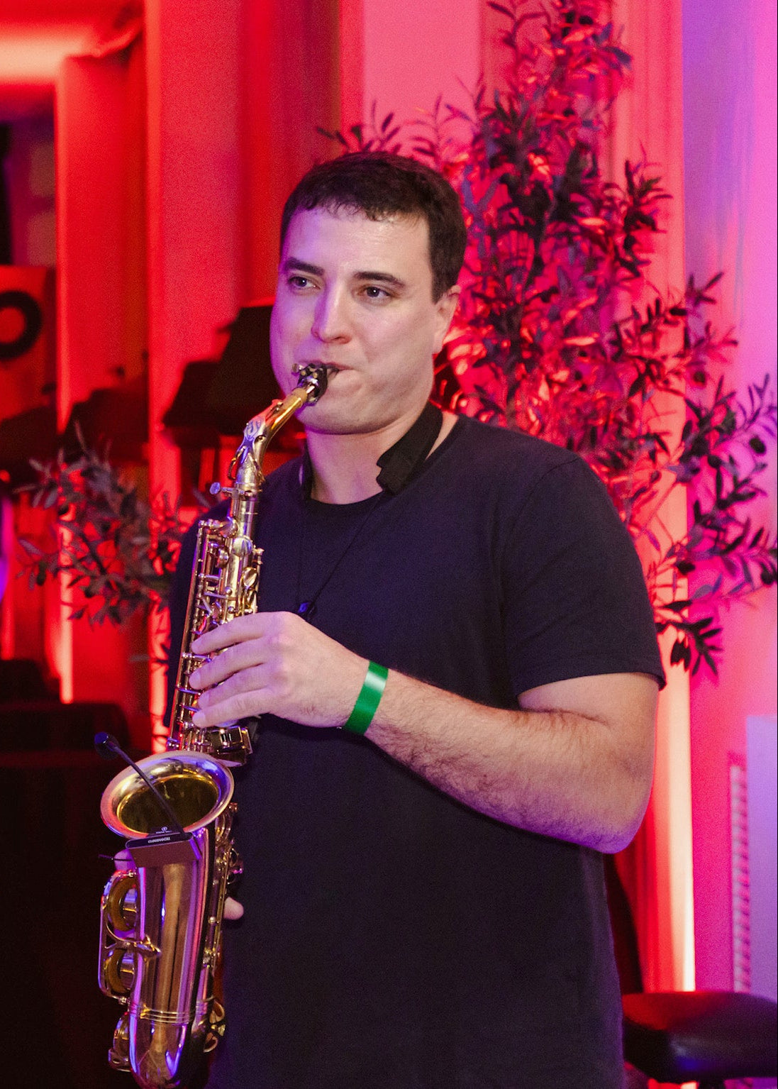 Man playing saxophone in a vibrant, neon-lit indoor setting with 'LOMO' sign.