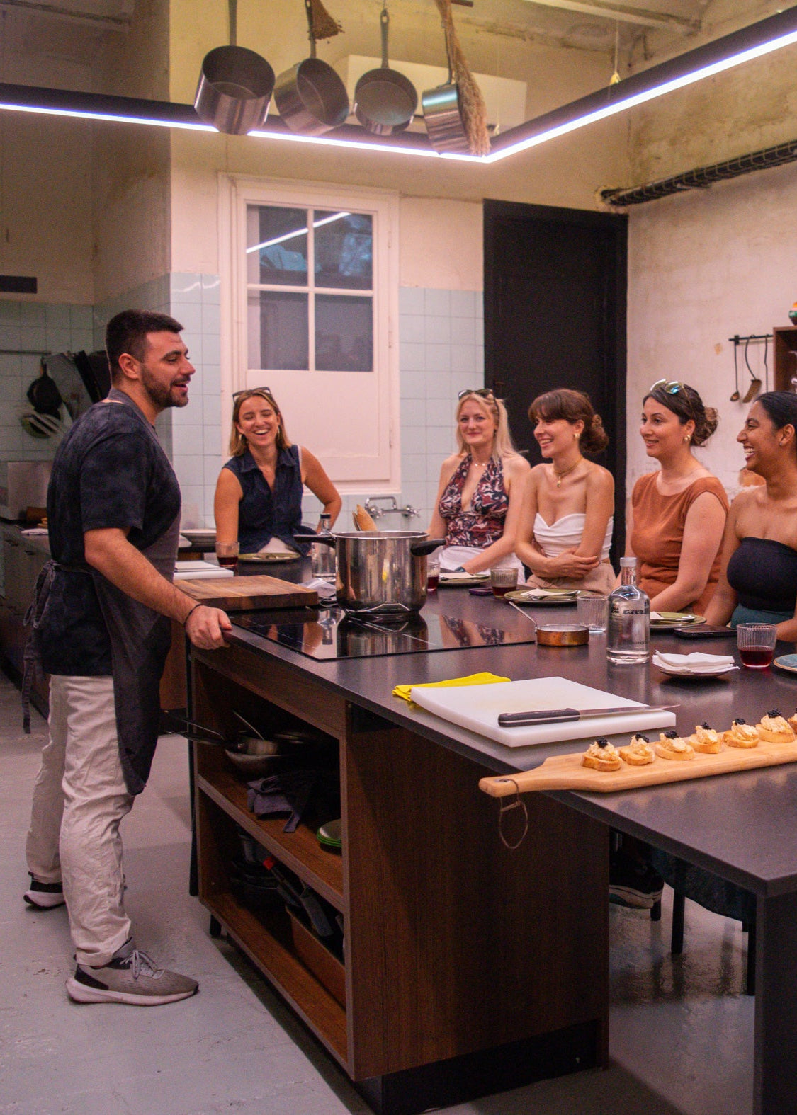 Group of people in a kitchen setting, possibly participating in a cooking class or event.