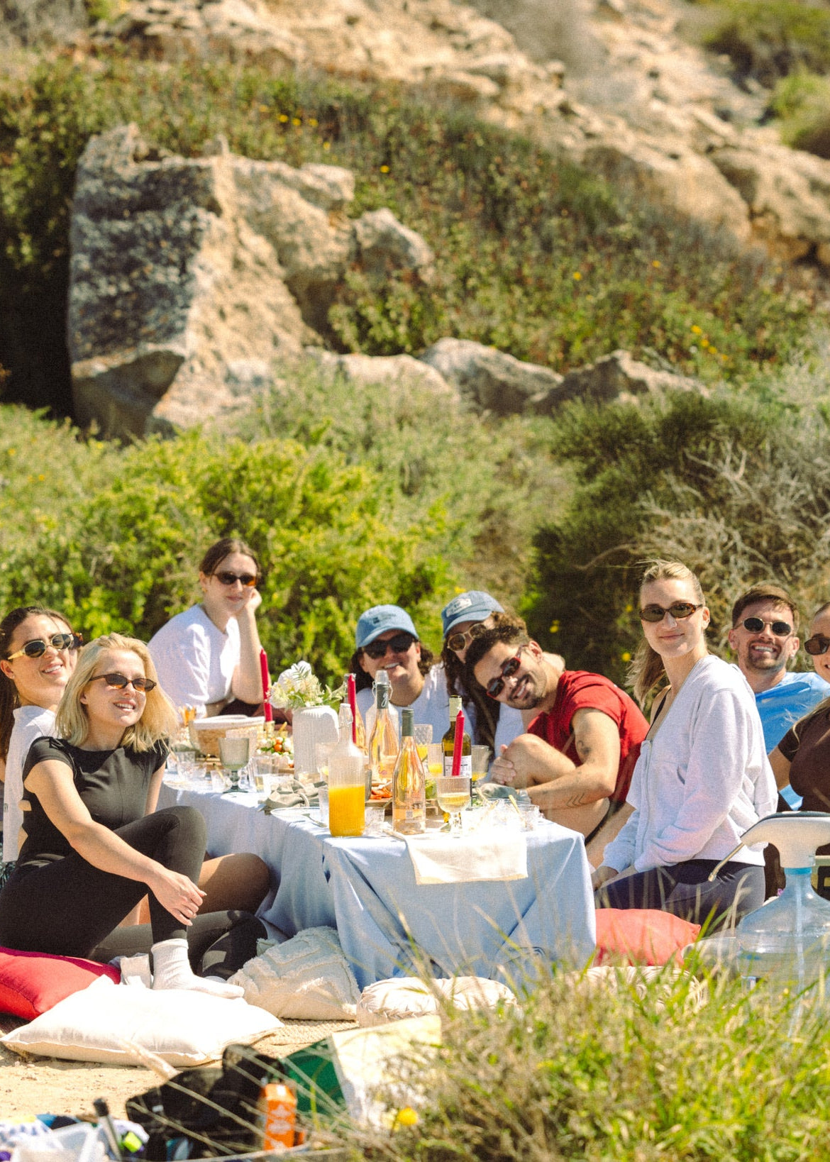 Group of people enjoying a picnic in a natural setting with a person taking a photo.