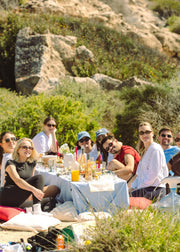 Group of people enjoying a picnic in a natural setting with a person taking a photo.