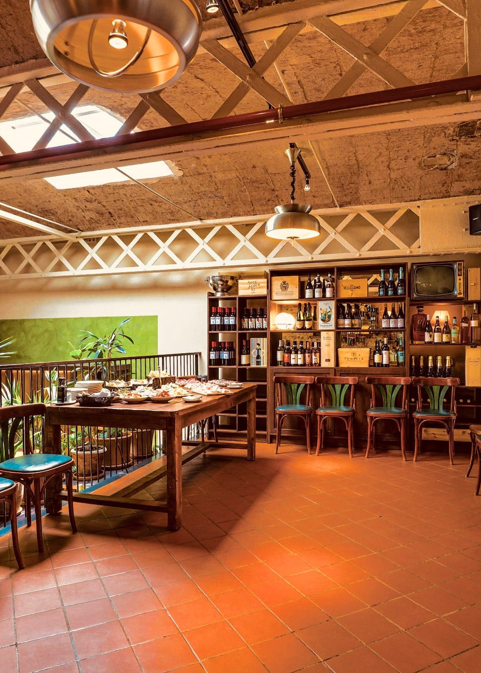 Restaurant interior with wooden tables and chairs, decorative ceiling, and shelves.