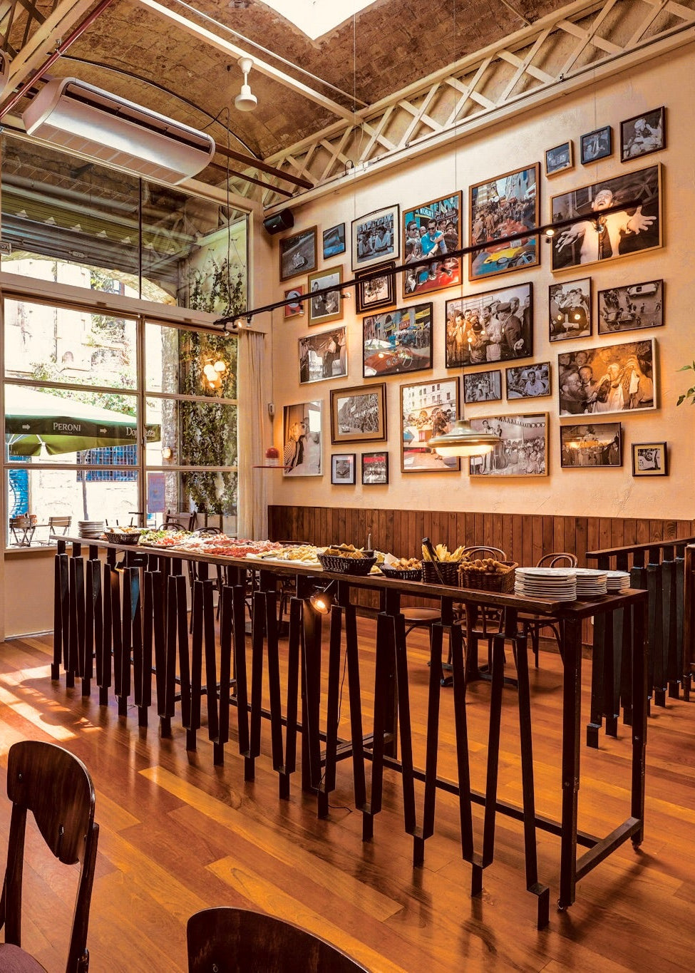 Modern cafe interior with wooden tables, chairs, and a wall of framed pictures.