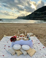 Scenic romantic picnic in Maresme featuring a curated grazing board, soft cushions, a cozy blanket, and elegant floral decor, perfect for a memorable couple’s outdoor experience.