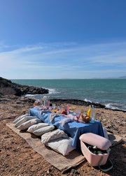 Dining table set up on a rocky beach with ocean view