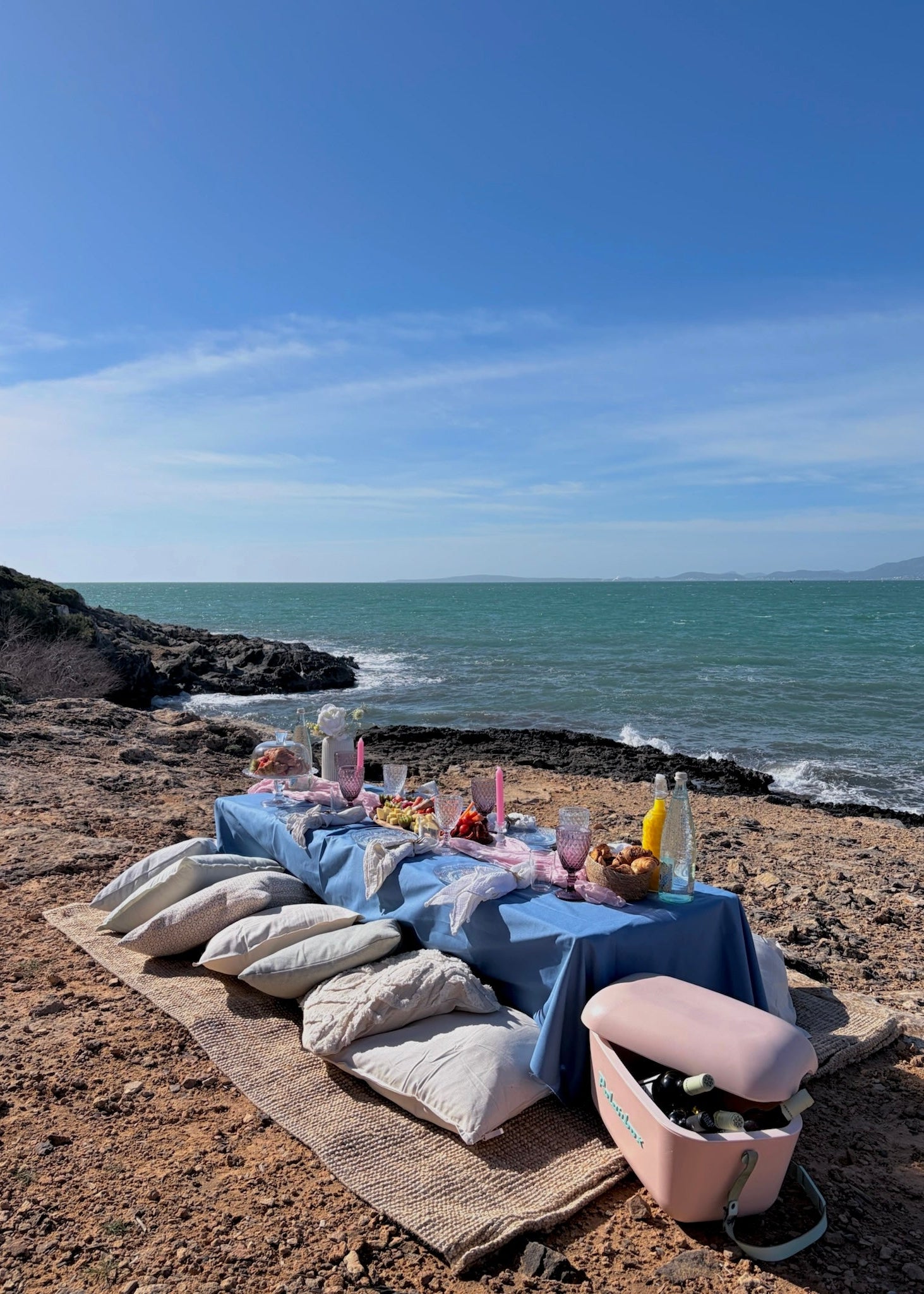 Dining table set up on a rocky beach with ocean view