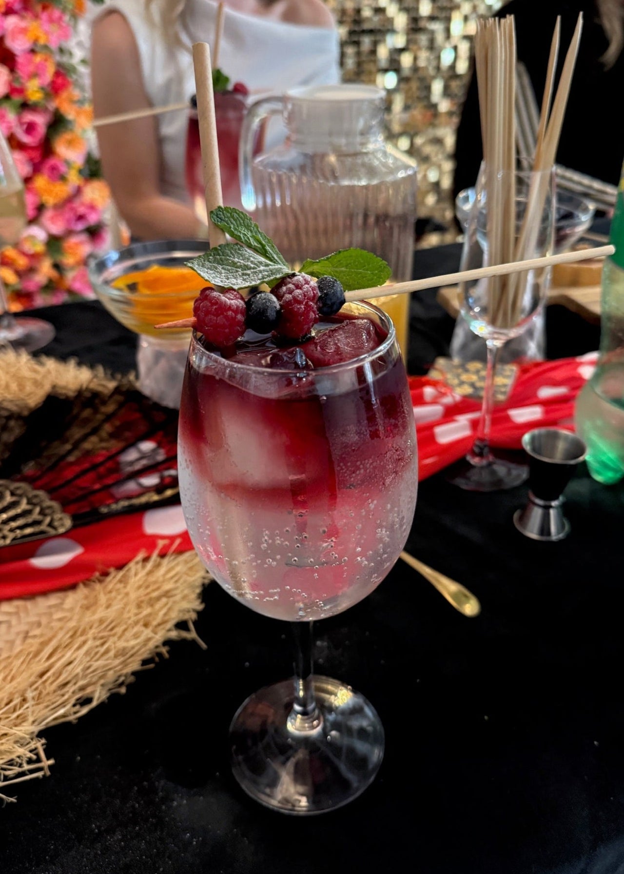 Decorative cocktail with berries and a skewer on a table with a blurred background