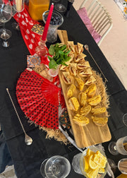 Decorative table setting with yellow flowers, red fan, and other items on a black tablecloth.