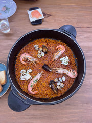 Seafood paella in a black pan on a wooden table