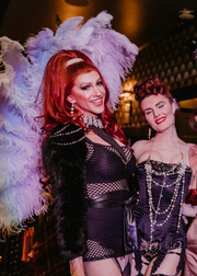 Two women in elaborate costumes with feathers and makeup, posing together.