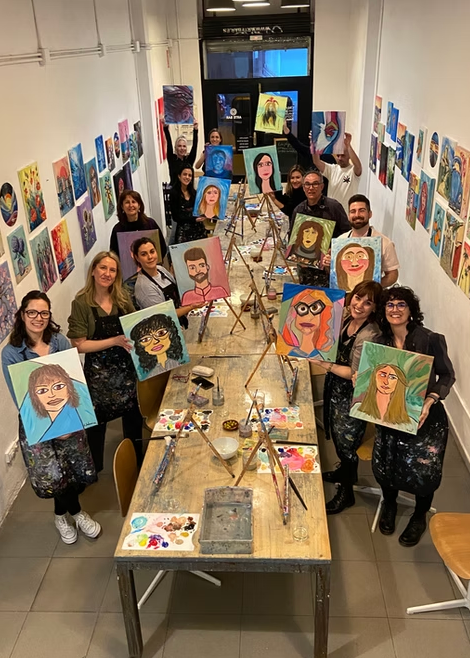 Group of people in a studio holding their painted portraits