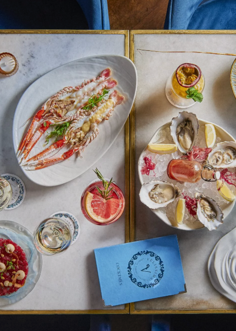 Top-down view of a table with various dishes and a menu on a marble surface.
