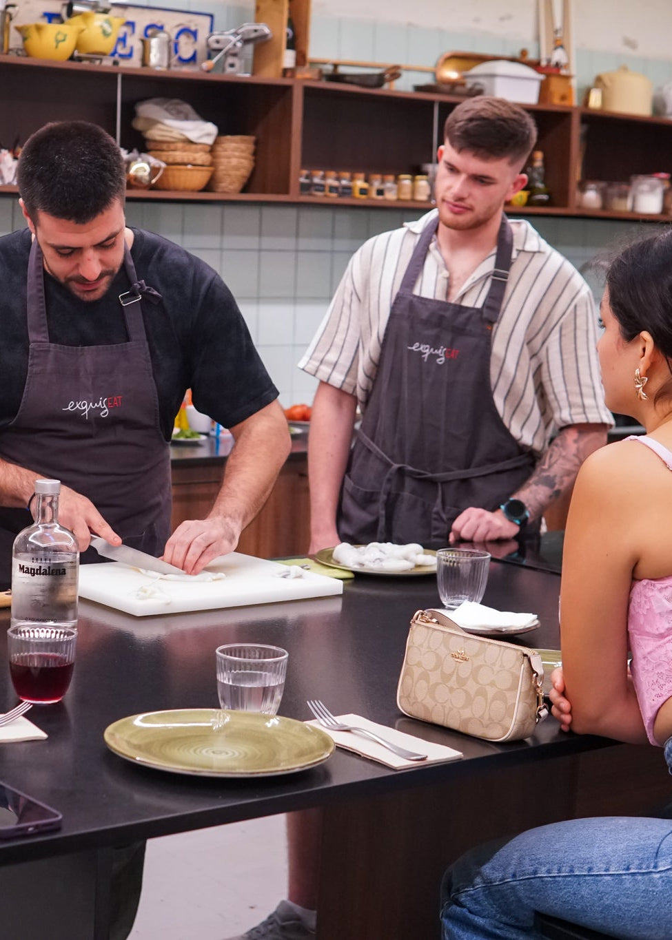 Group of people in a kitchen setting with one person cutting food on a counter.