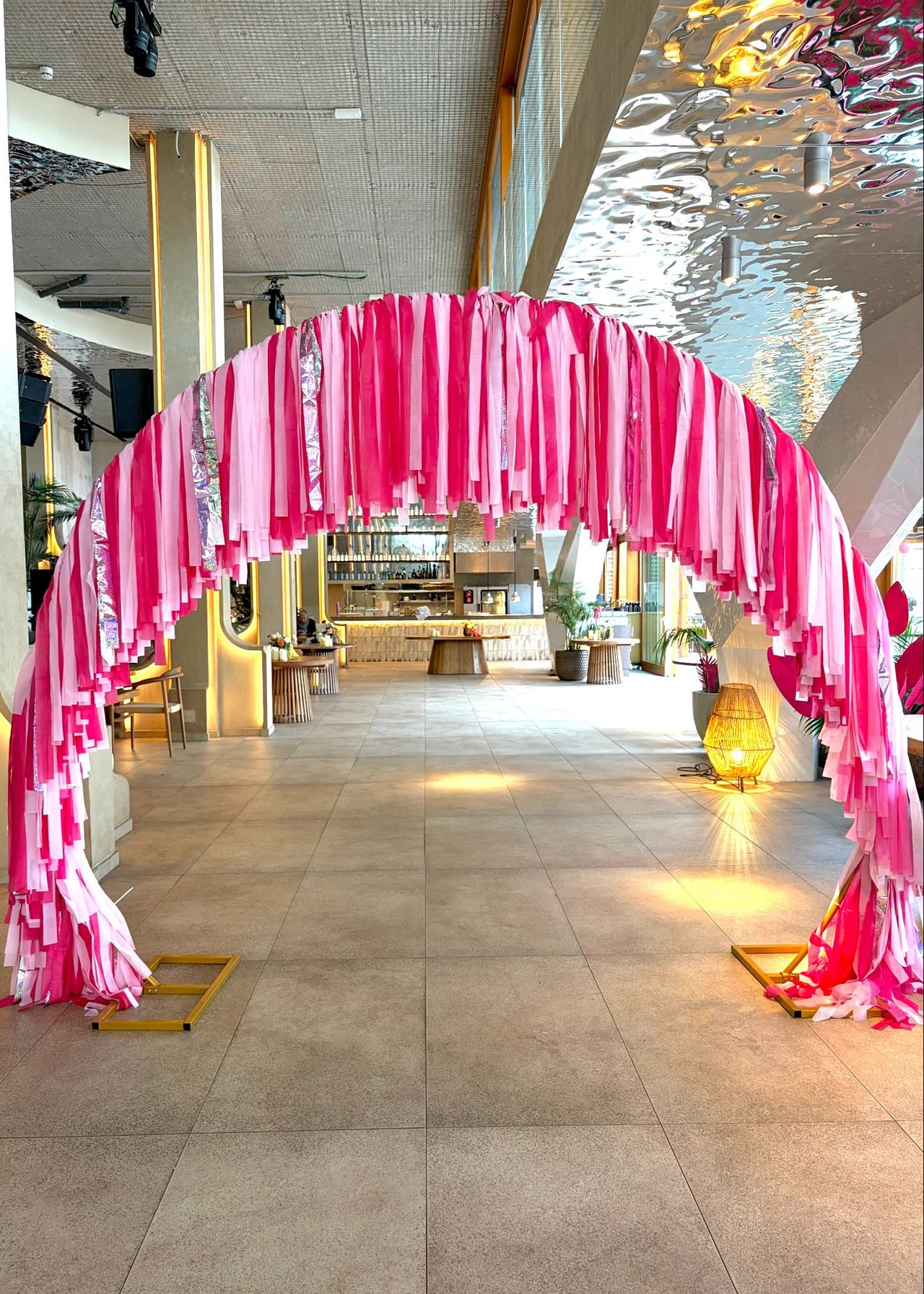 Pink and white fabric archway in a modern indoor setting with reflective ceiling