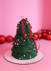 Green Christmas tree-shaped cake with red ribbons on a pink background