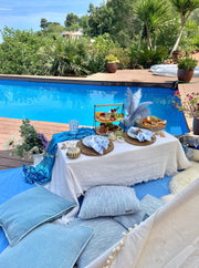 Charming romantic picnic setup with a picnic basket, gourmet treats, plush pillows, and candles, creating a cozy atmosphere for a couple's outdoor rendezvous in Barcelona.